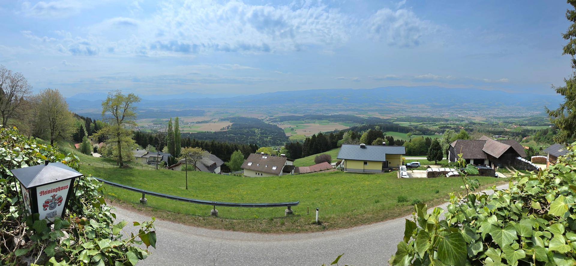 Panoramablick über die hügelige Landschaft mit verstreuten Häusern und weitem Horizont.