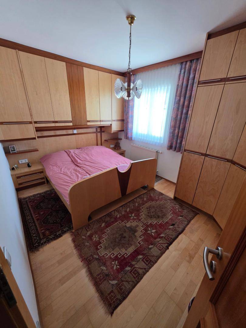 Schlafzimmer mit Holzmöbeln, einem Doppelbett und einem Teppich, das eine gemütliche Atmosphäre schafft.