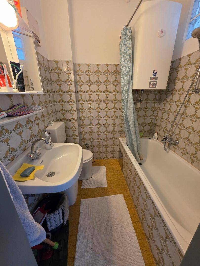Badezimmer mit Badewanne, Waschbecken und WC, gefliest in einem traditionellen Muster.
