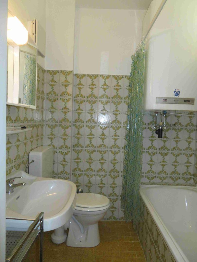 Badezimmer mit Badewanne, Waschbecken und WC, gefliest in einem traditionellen Muster.
