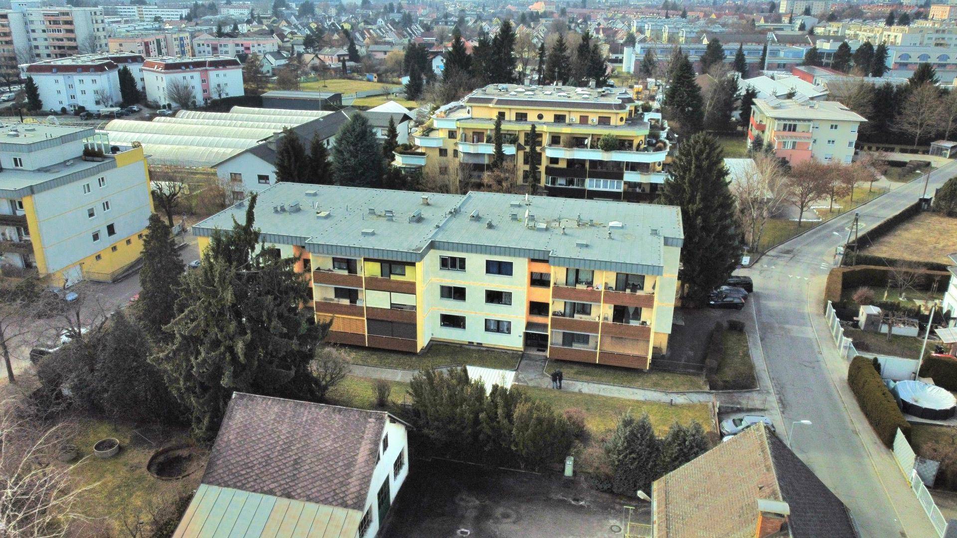 Luftaufnahme eines Mehrfamilienhauses mit Flachdach und umliegender Wohnbebauung.