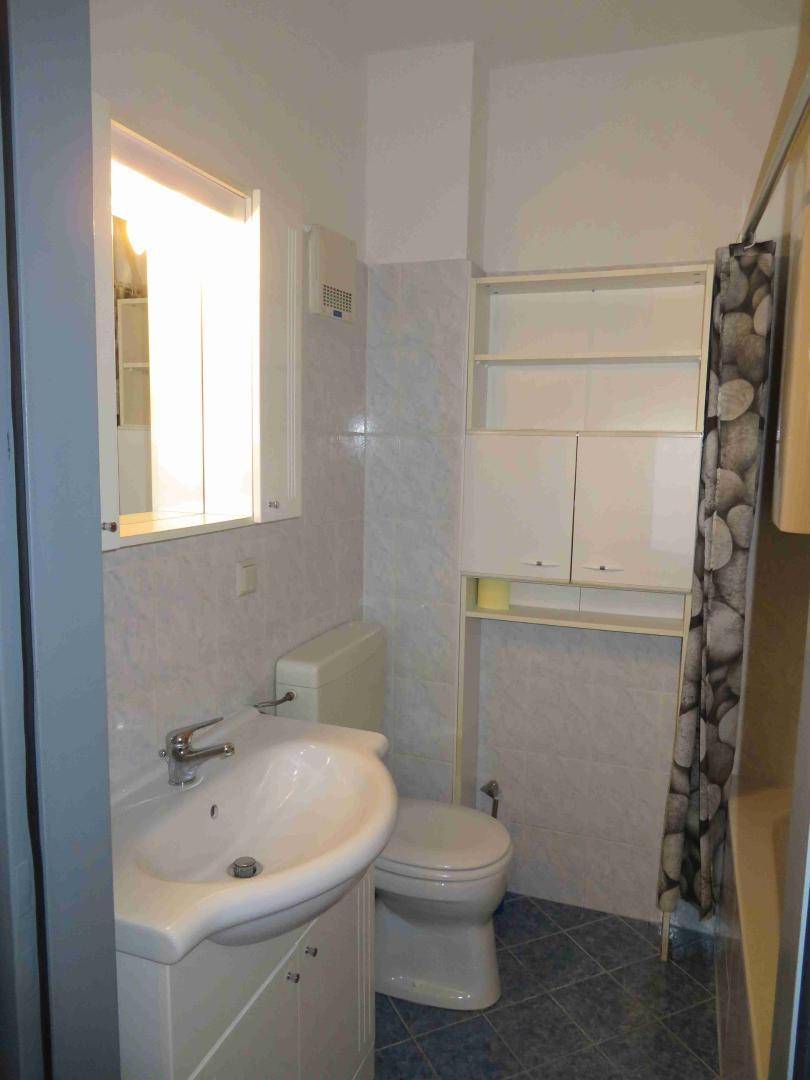 Badezimmer mit Waschbecken, WC und Badewanne, hell gefliest und mit Fenster.