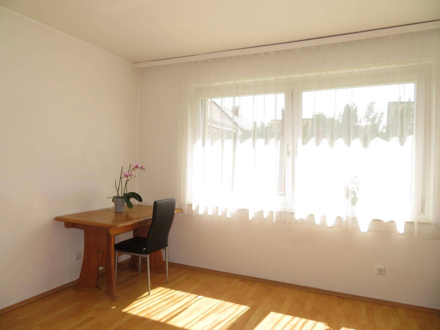Heller Raum mit Holzboden, kleinem Tisch und Stuhl, ideal als Arbeitsbereich nutzbar.