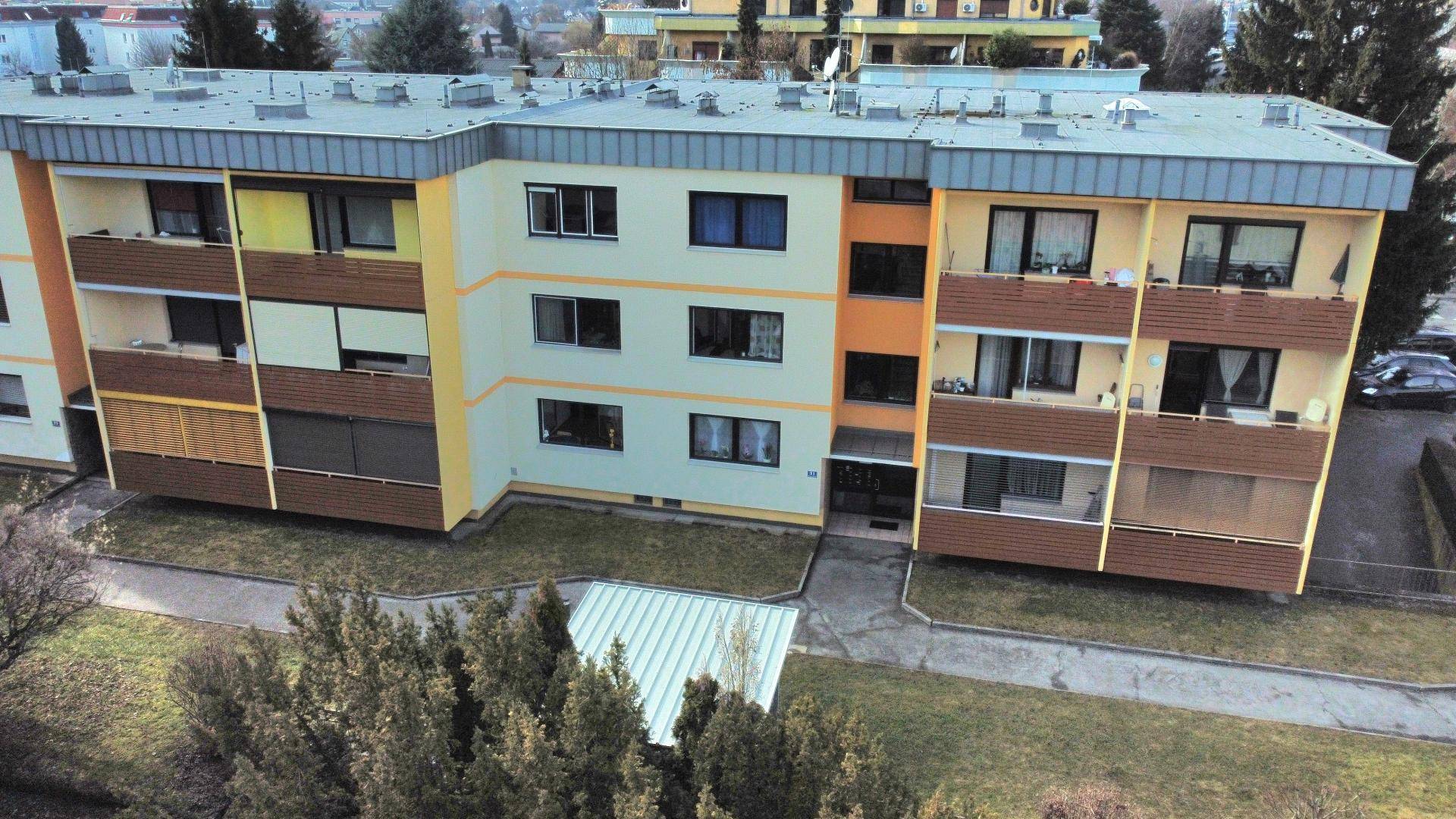 Nahaufnahme der Fassade eines Mehrfamilienhauses mit Balkonen und Fenstern.