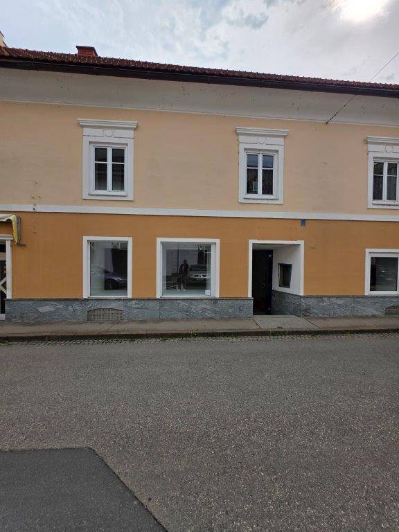 Fassade eines Gebäudes mit großen Schaufenstern im Erdgeschoss und Wohnfenstern in den oberen Etagen.