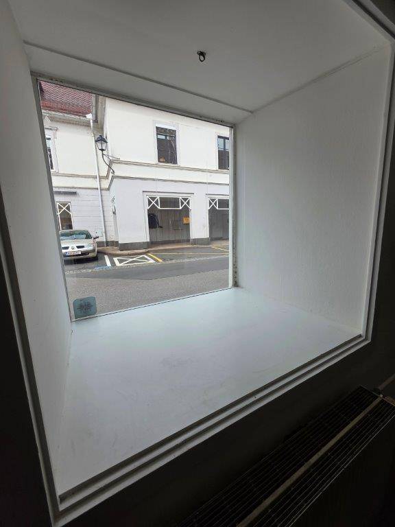Blick aus einem großen Fenster auf eine Straße mit einem Gebäude und einem geparkten Auto.