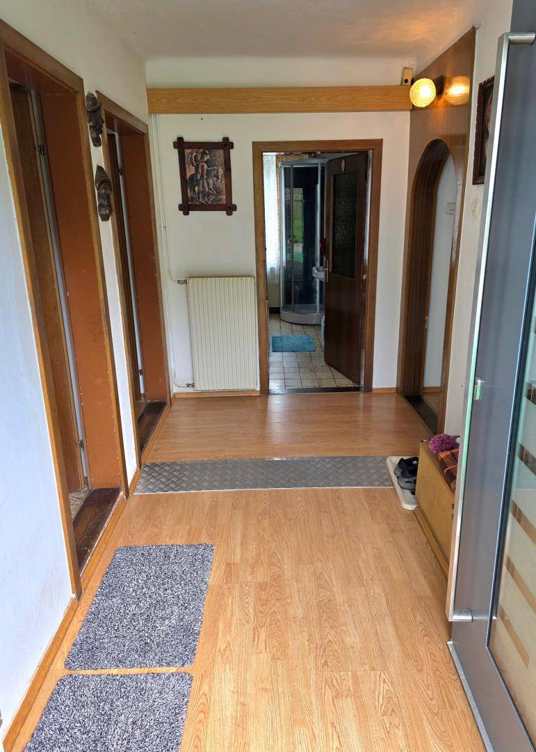 Heller Flur mit Laminatboden und Holztürrahmen, der zu verschiedenen Räumen führt.