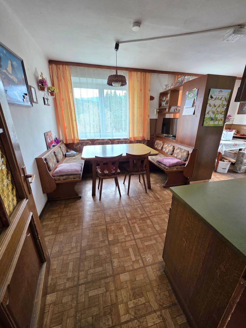 Gemütlicher Essbereich mit Holztisch und Eckbänken, beleuchtet durch ein Fenster mit Blick ins Grüne.