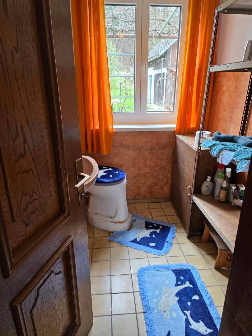 Separates WC mit Toilette, Fenster und gefliestem Boden, einfach und funktional.