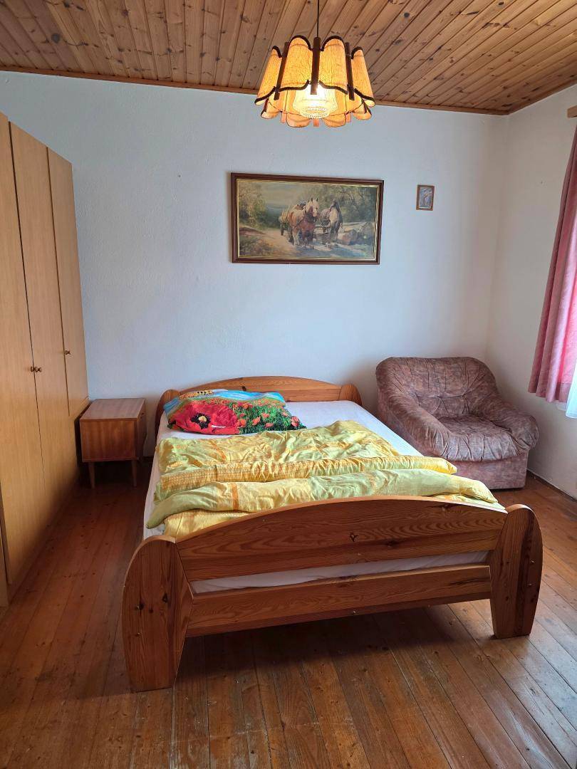 Schlafzimmer mit Doppelbett, Holzdecke und Kleiderschrank, gemütlich eingerichtet.