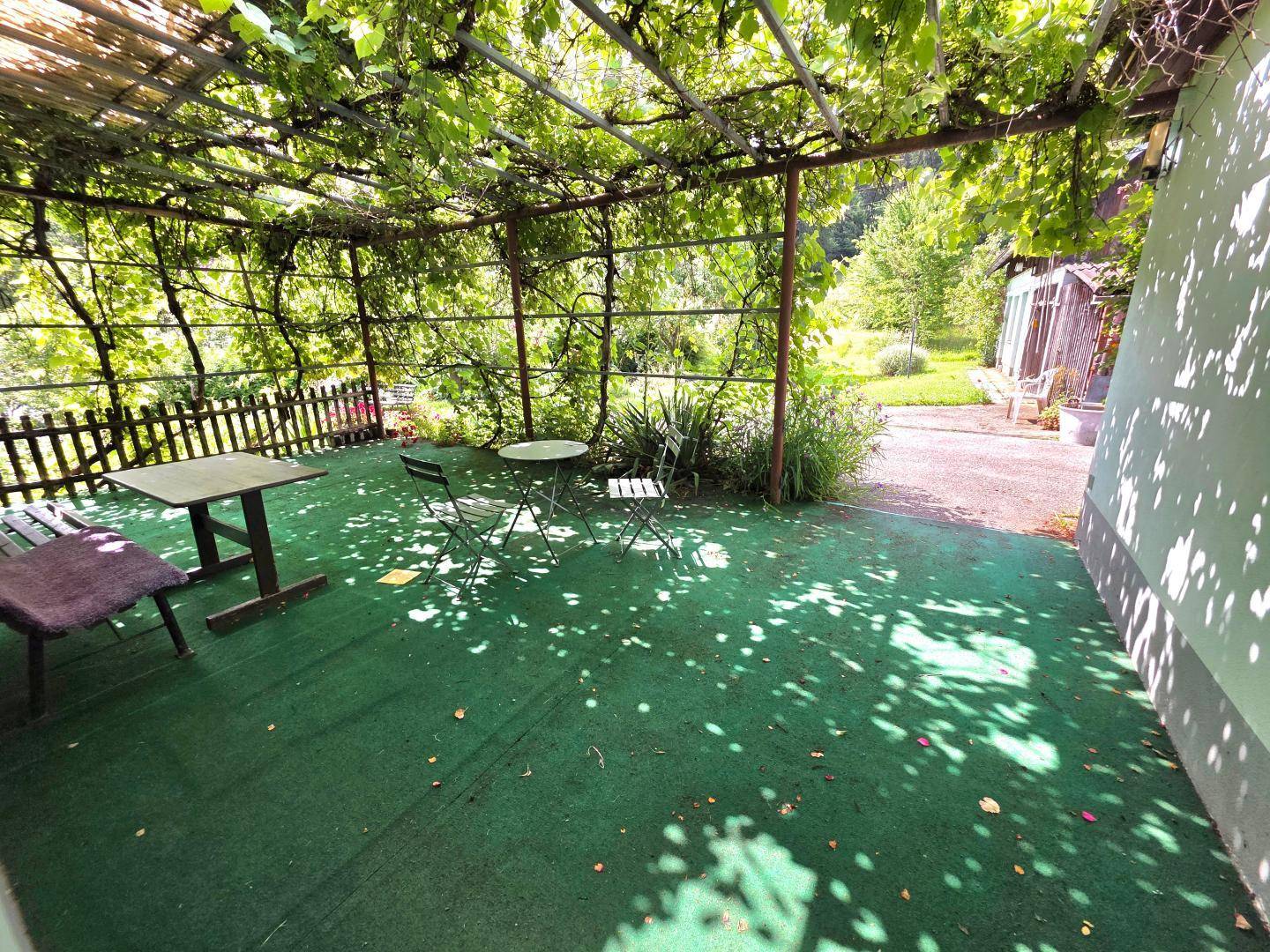 Gemütliche, überdachte Terrasse mit Gartenmöbeln und Blick ins Grüne, ideal für entspannte Stunden.