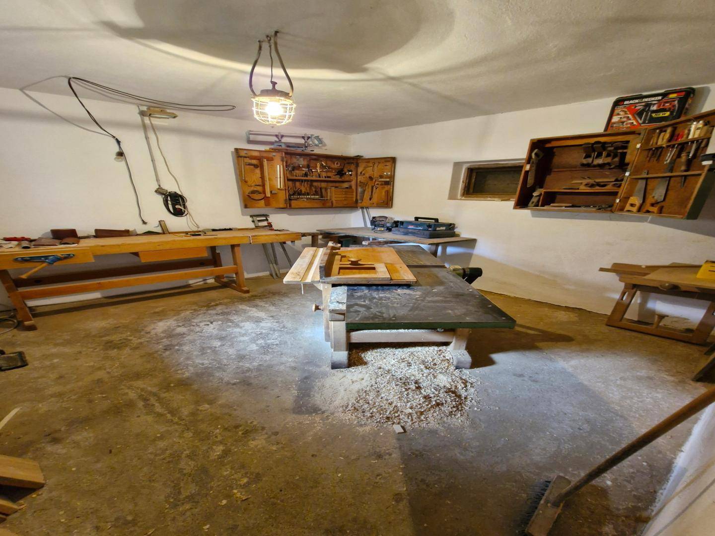 Werkstatt mit verschiedenen Holzbearbeitungsmaschinen, Werkbänken und Betonboden, ideal für Handwerker.