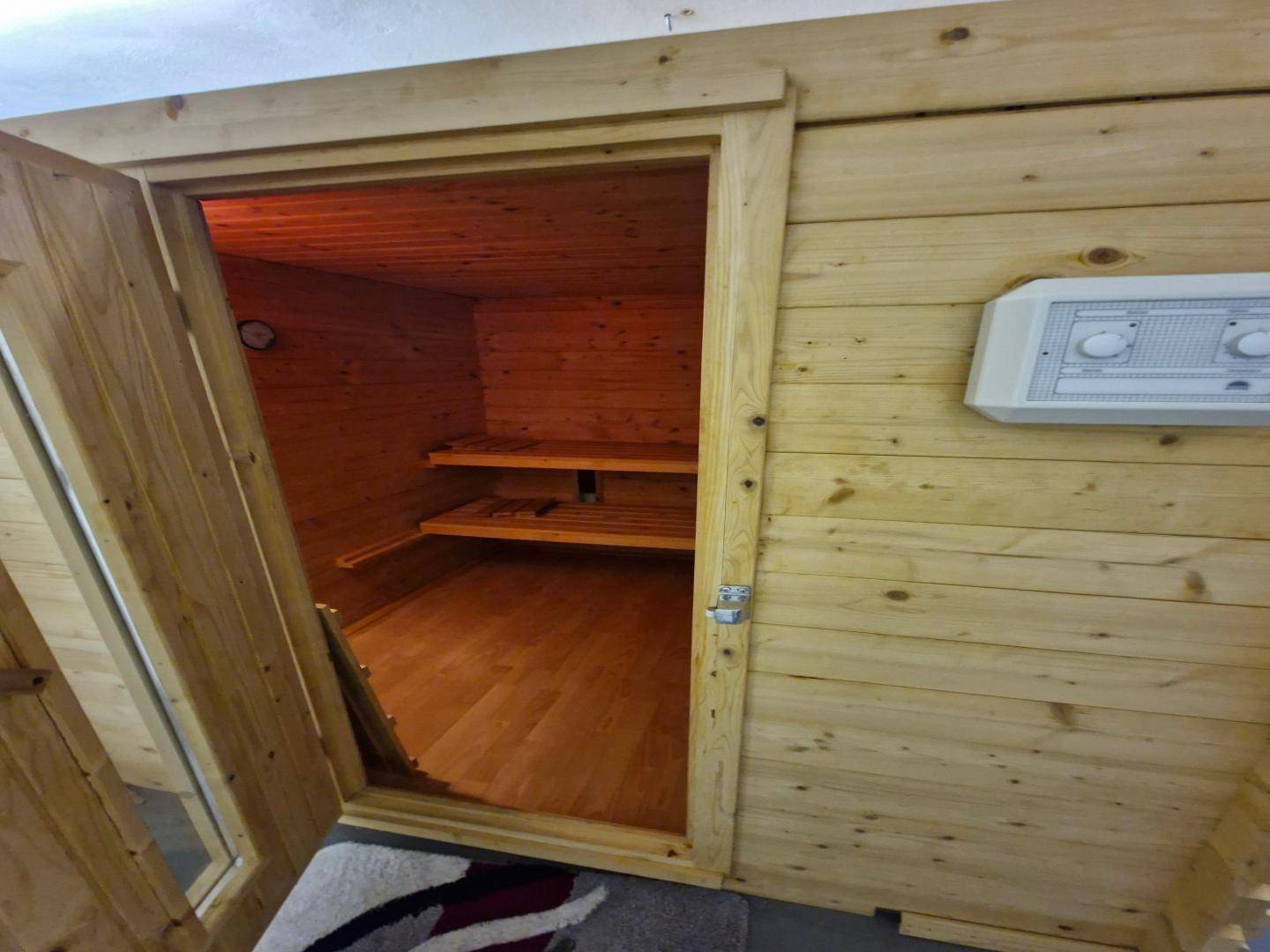Gemütliche Holzsauna mit Bänken und Steuerungselementen, bereit für entspannende Momente.