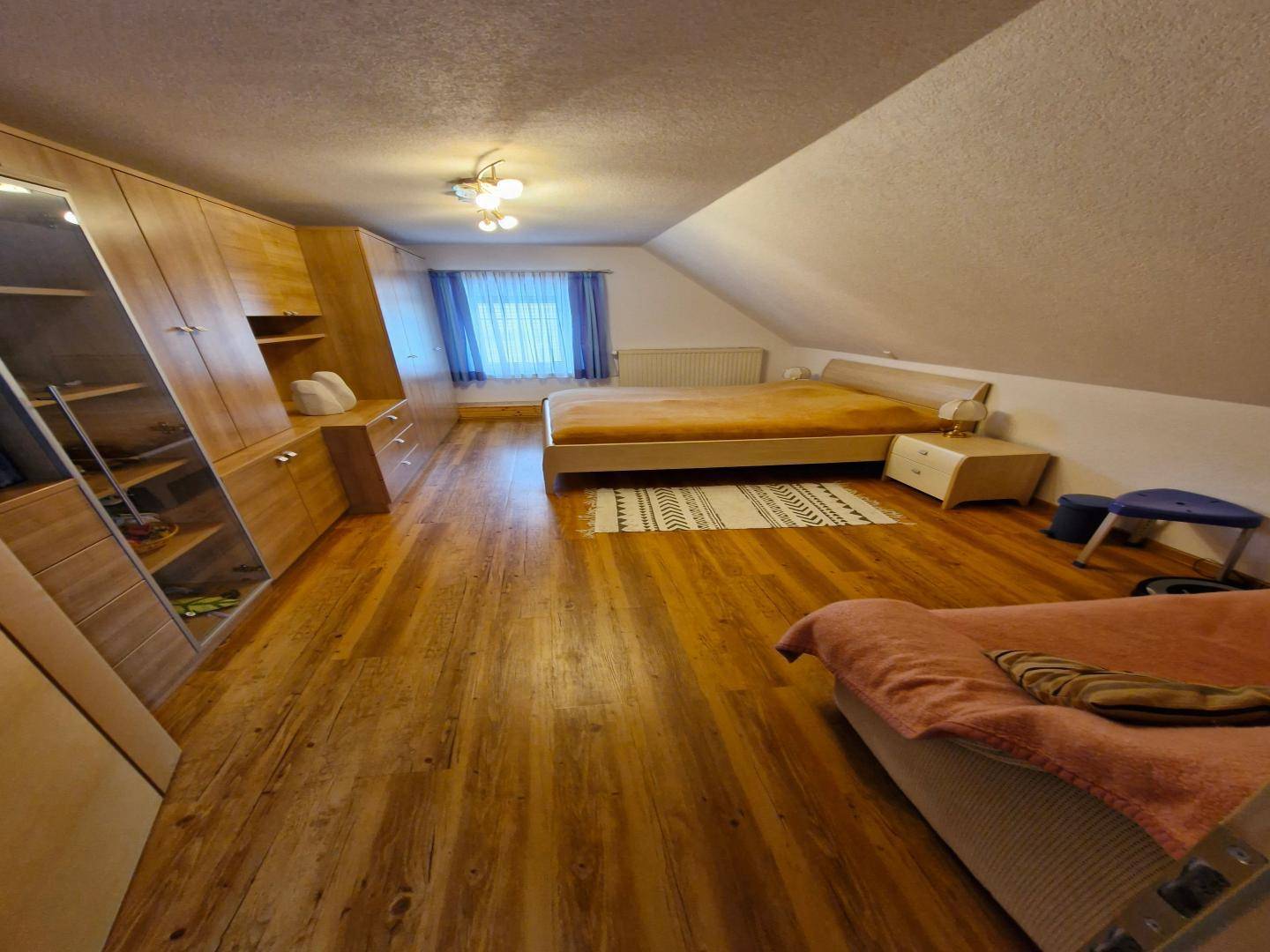Gemütliches Schlafzimmer im Dachgeschoss mit Holzboden, zwei Betten und viel Stauraum in Holzschränken.