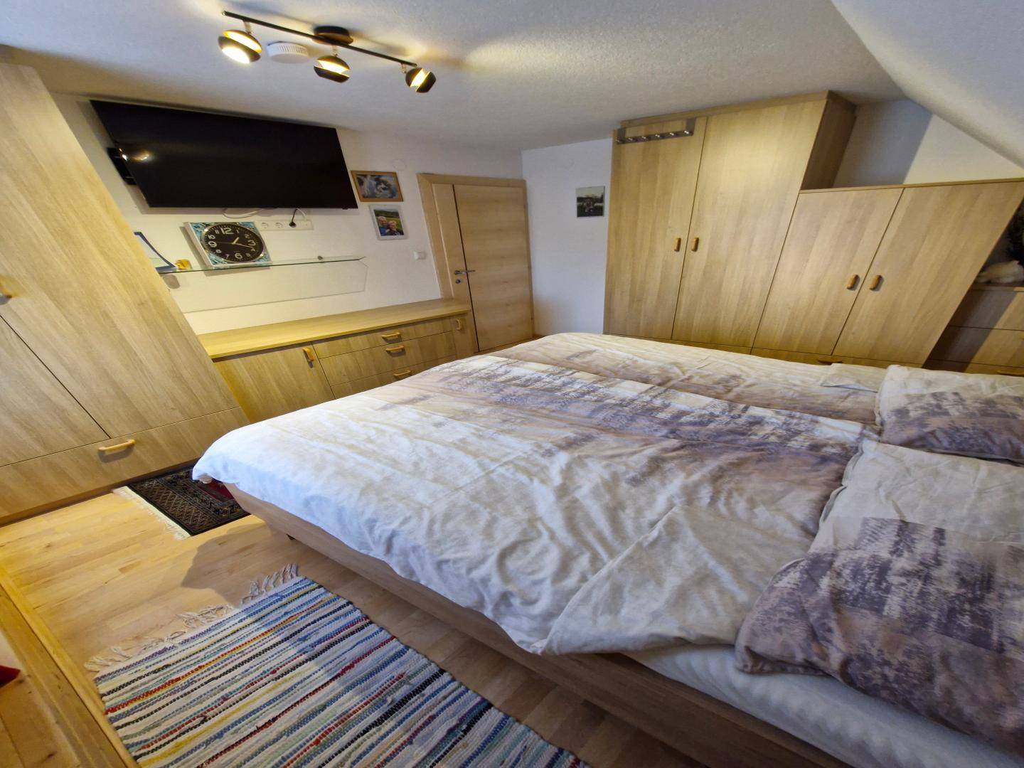 Gemütliches Schlafzimmer im Dachgeschoss mit Doppelbett, Holzschränken und Dachschräge.