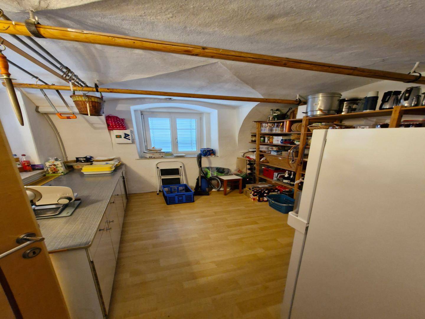 Praktischer Abstellraum mit Gewölbedecke, Holzregalen und einem Fenster für Belüftung.