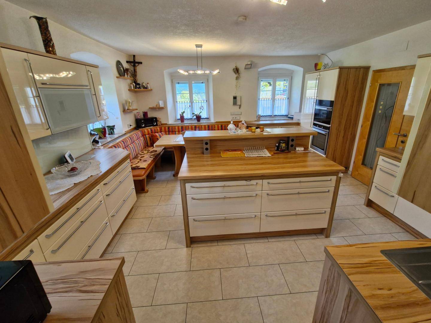 Helle Küche mit Holzarbeitsplatten, Kücheninsel und einer gemütlichen Essecke mit Eckbank.