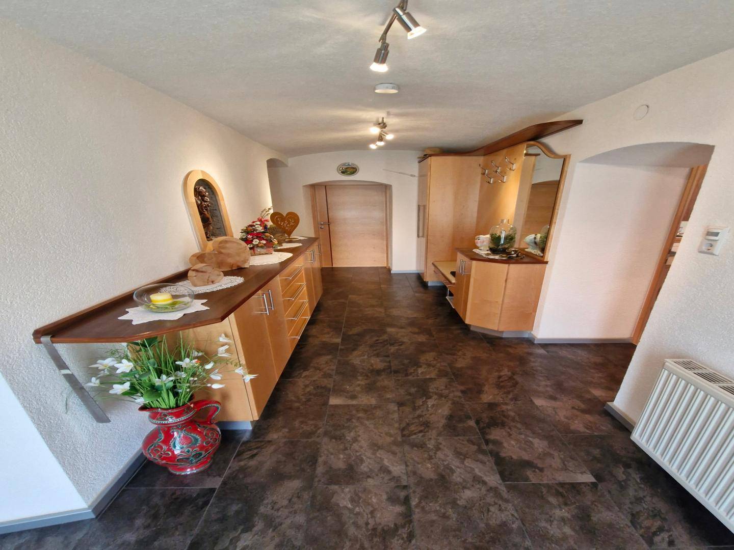 Geräumiger Flur mit dunklen Fliesen, eleganten Holzmöbeln und einem großen Spiegel.