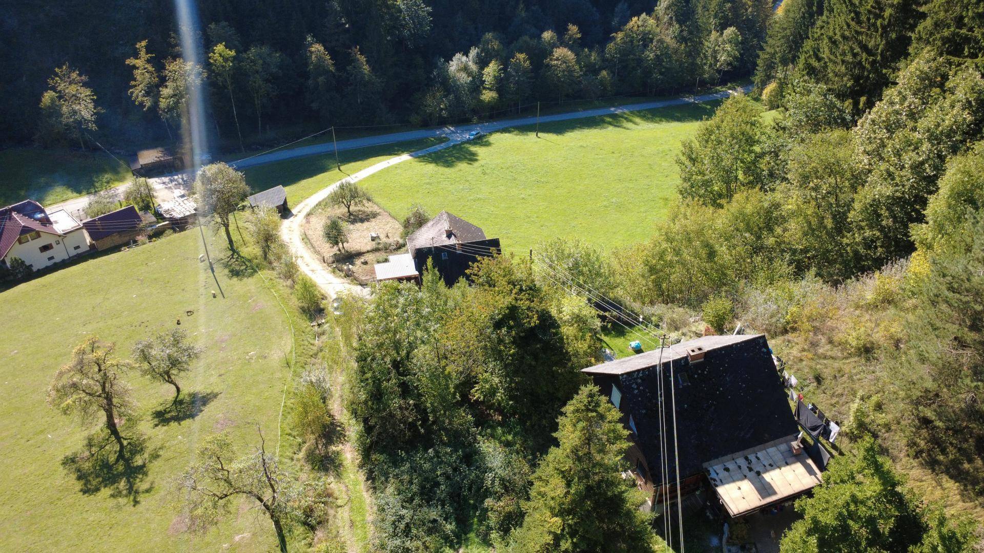 Weitläufige Luftaufnahme des Anwesens mit mehreren Gebäuden, umgeben von Wald und Wiesen.