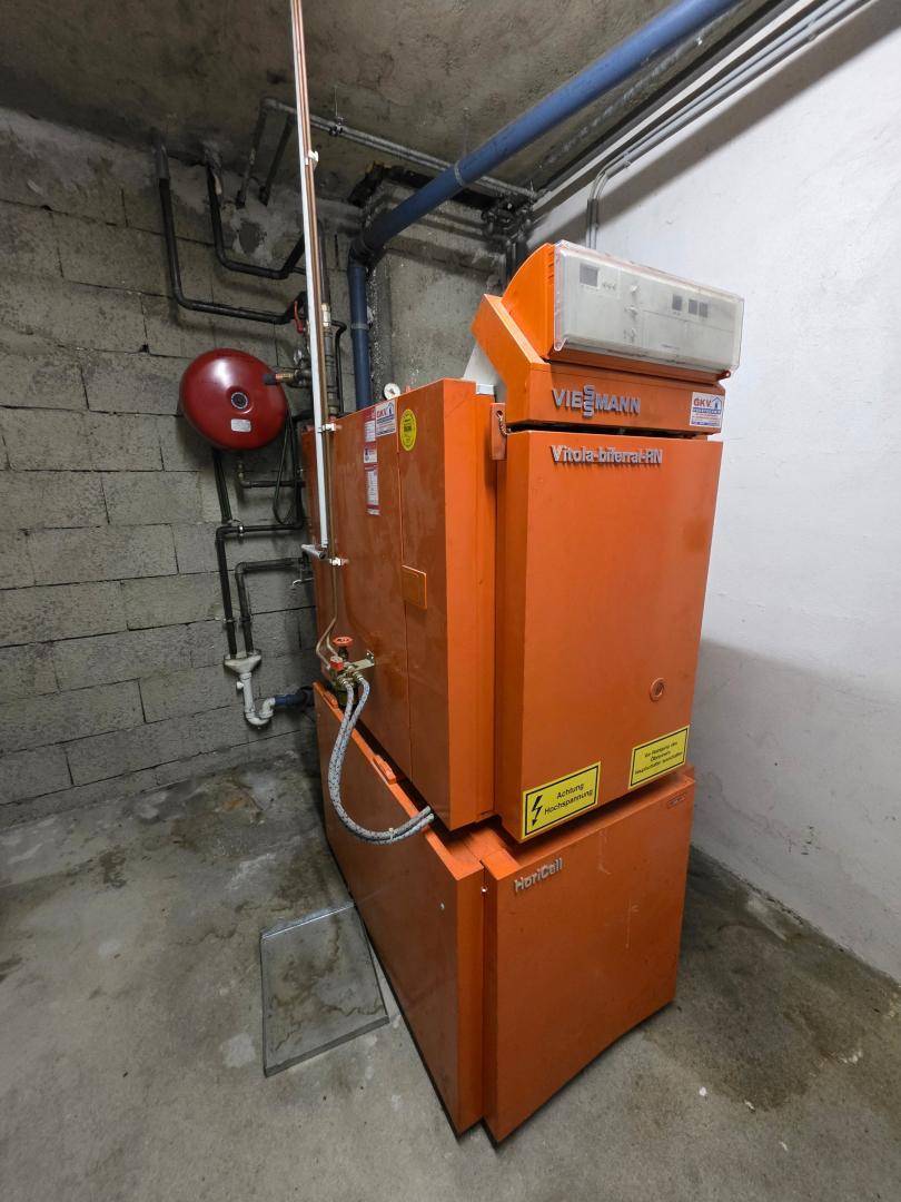 Orangefarbene Viessmann Ölheizung in einem Kellerraum mit Betonwänden und -boden.