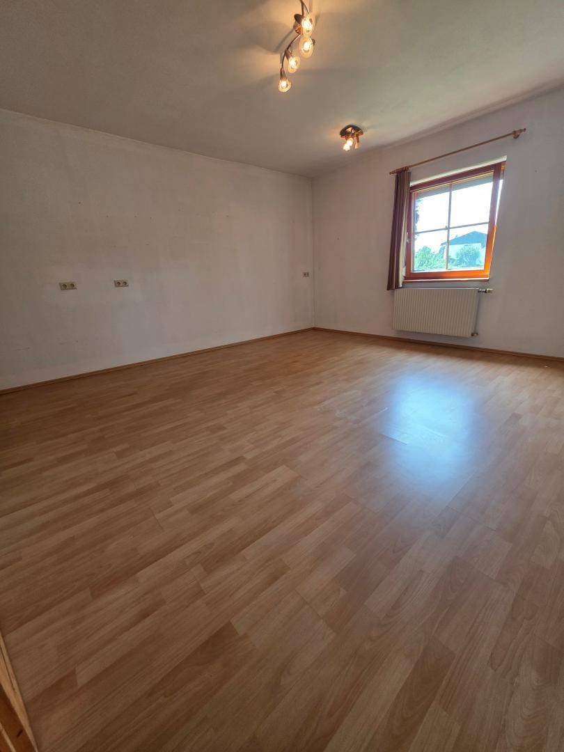 Helles Schlafzimmer mit Laminatboden und Fenster, bietet ausreichend Platz für Möbel.