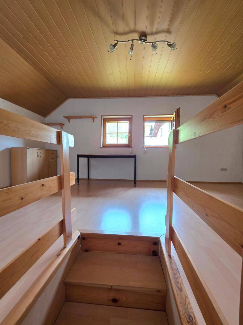 Geräumiges Schlafzimmer mit Holzdecke, Laminatboden und Etagenbetten, ideal für Kinder.