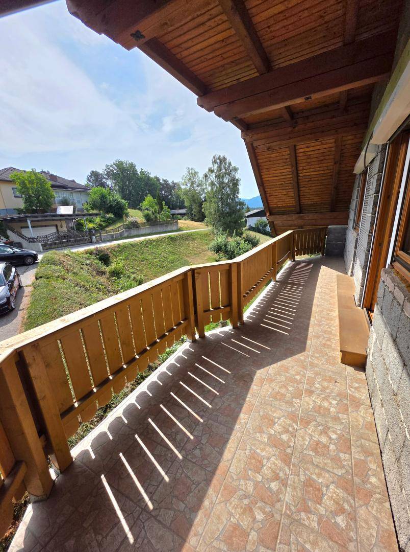 Sonniger Balkon mit Fliesenboden und Holzgeländer, ideal für entspannte Stunden im Freien.