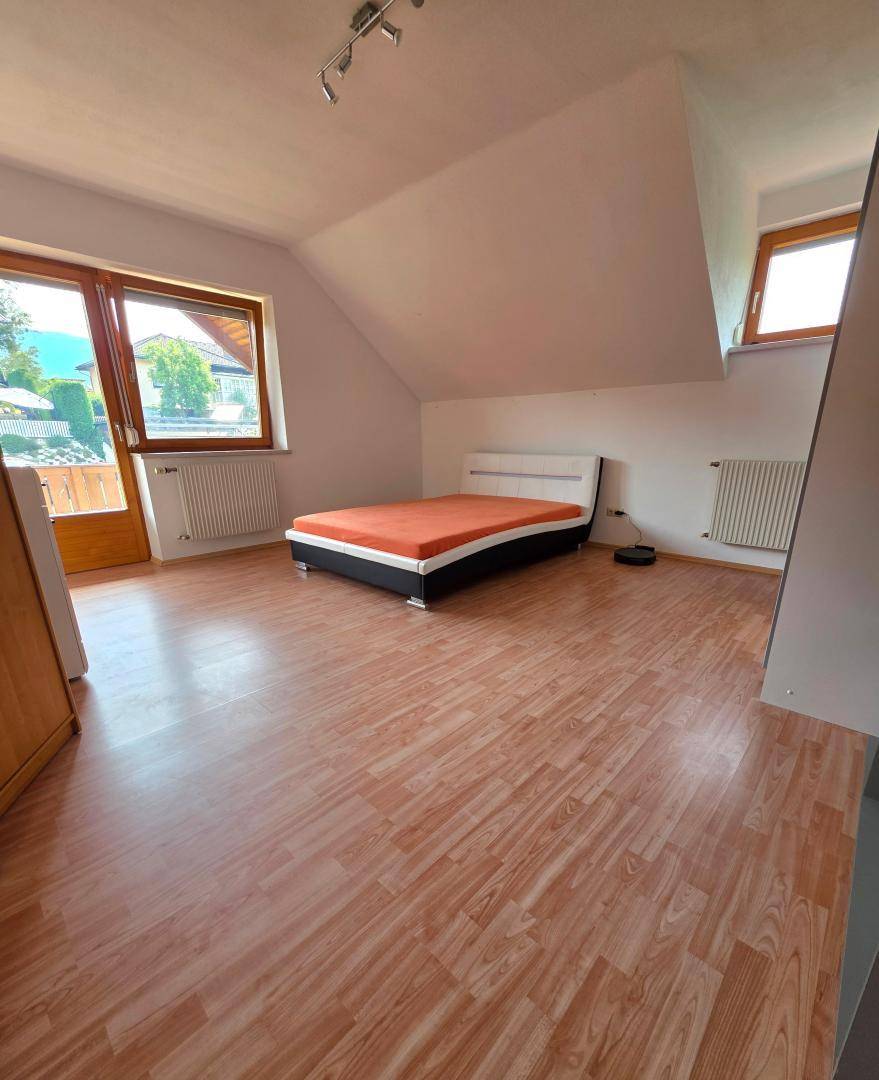 Helles Schlafzimmer mit Laminatboden, Doppelbett und Dachschräge, bietet viel Tageslicht.