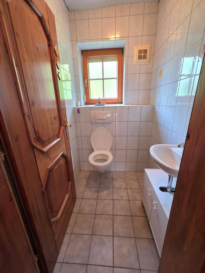 Separates WC mit Fliesenboden, Fenster und Wand-WC, in einem gepflegten Zustand.