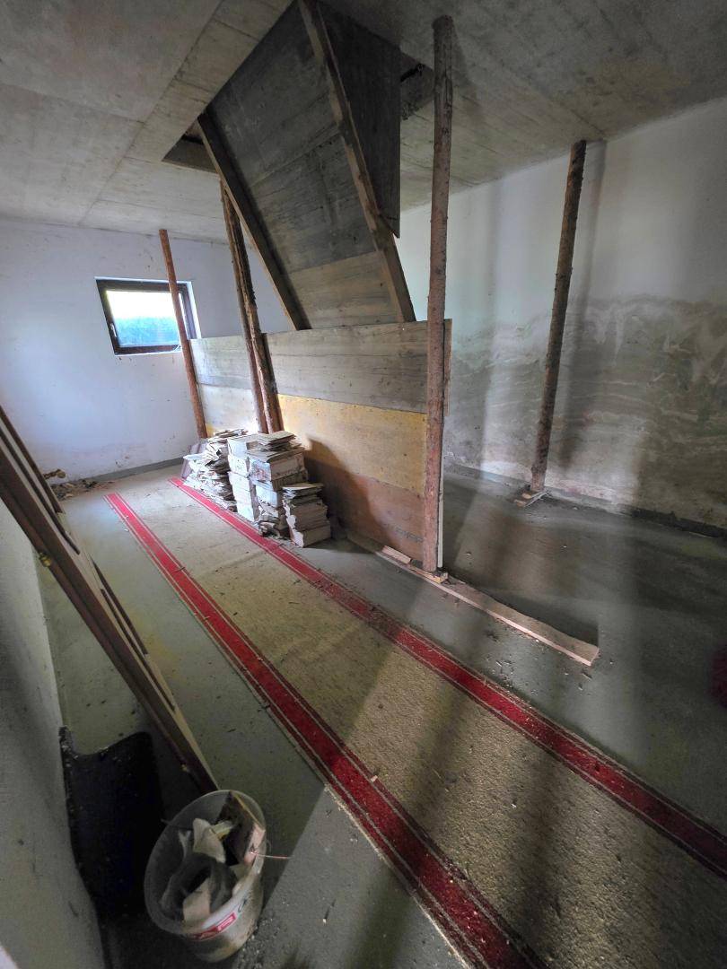 Unfertiger Kellerraum mit Fenster und Teppichläufern, bietet Stauraum.
