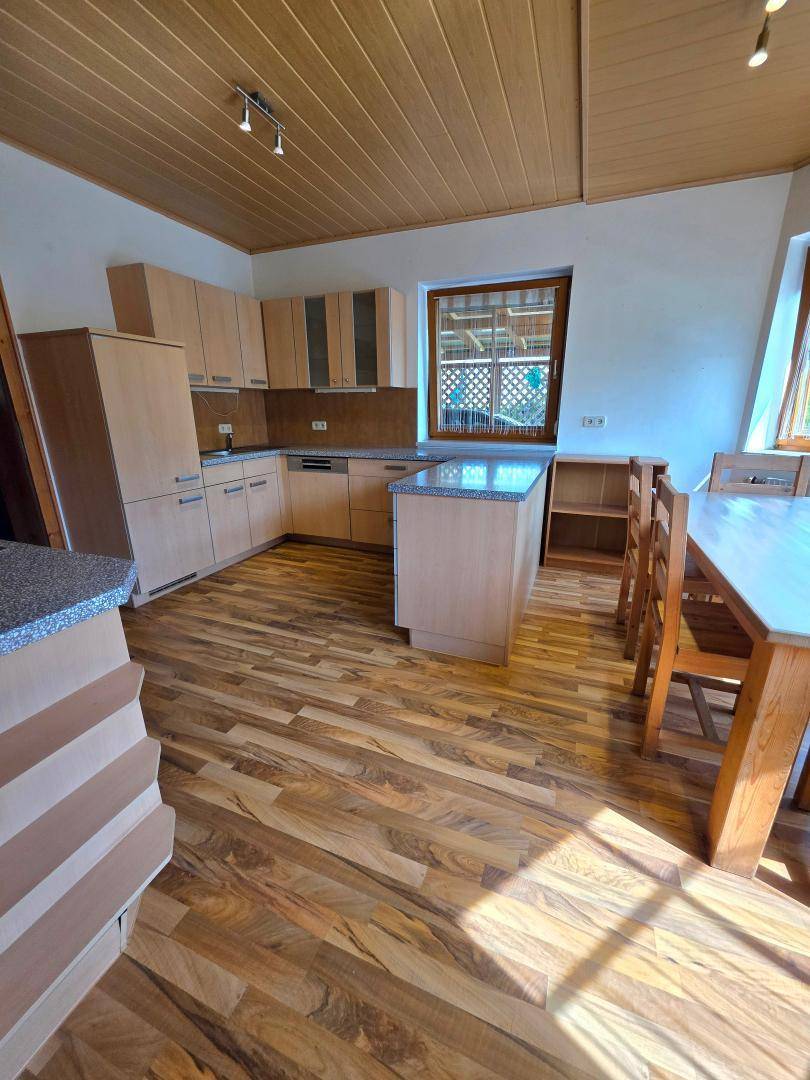 Helle Küche mit Holzdecke, Laminatboden und Essbereich, ausgestattet mit modernen Geräten.