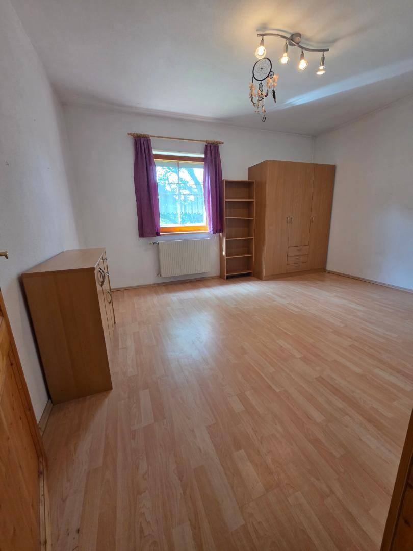 Schlafzimmer mit Laminatboden, Kleiderschrank und Fenster, in einem gepflegten Zustand.