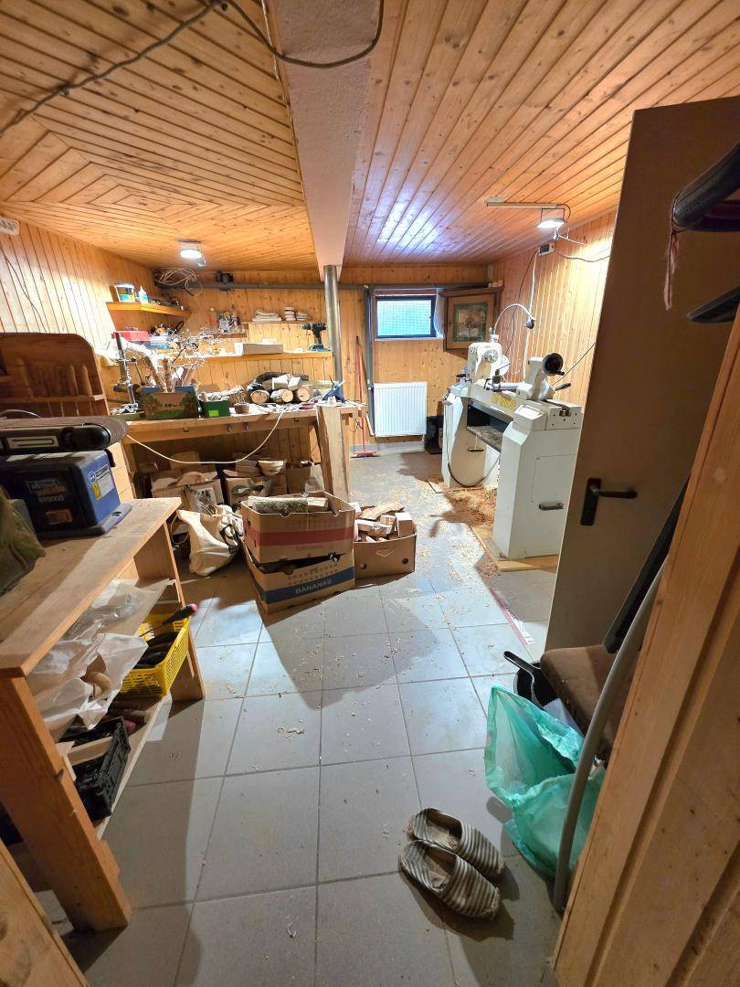 Werkstatt im Keller mit Holzverkleidung, Werkbänken und Maschinen, ideal für handwerkliche Arbeiten.