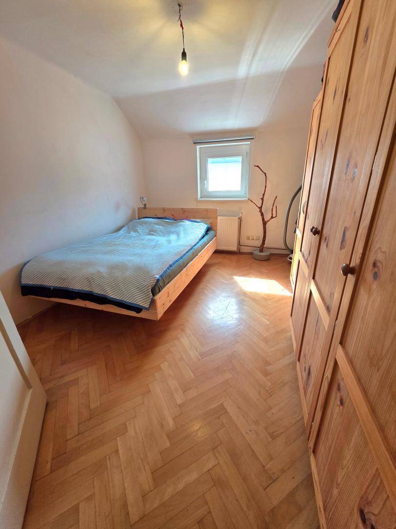 Gemütliches Schlafzimmer mit Holzbett, großem Holzschrank und klassischem Fischgrätparkett.