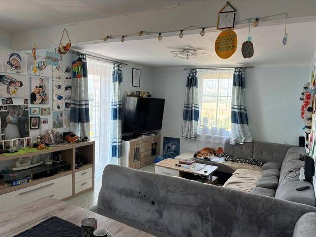 Gemütliches Wohnzimmer mit großem Ecksofa, Fernseher und Zugang zu einem Außenbereich.