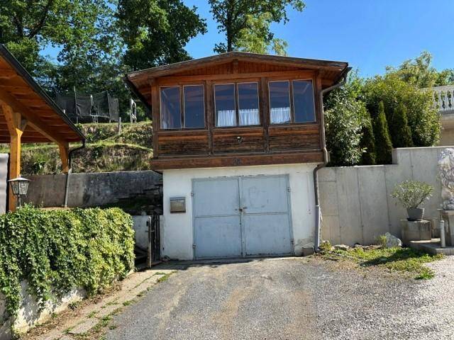 Separate Garage mit Holzanbau im Obergeschoss und einem weißen Garagentor.