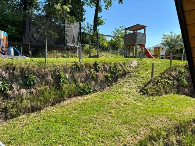 Gartenbereich mit Spielplatzstruktur, Rutsche und Trampolin, ideal für Kinder.