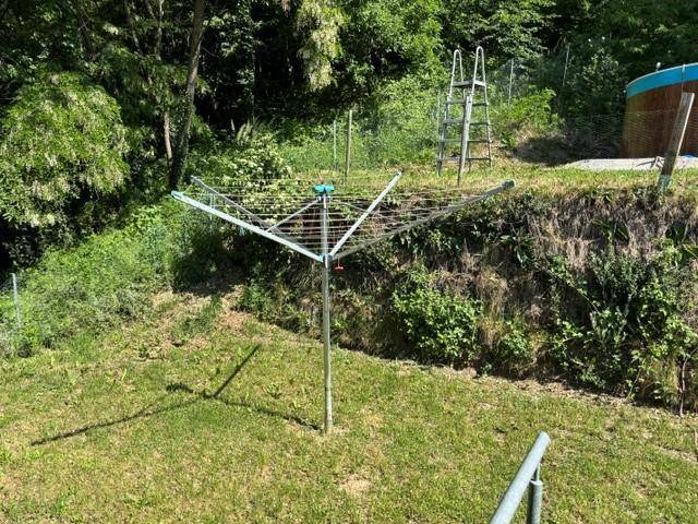 Grüner Gartenbereich mit Wäschespinne, Rasenfläche und umgebenden Bäumen.