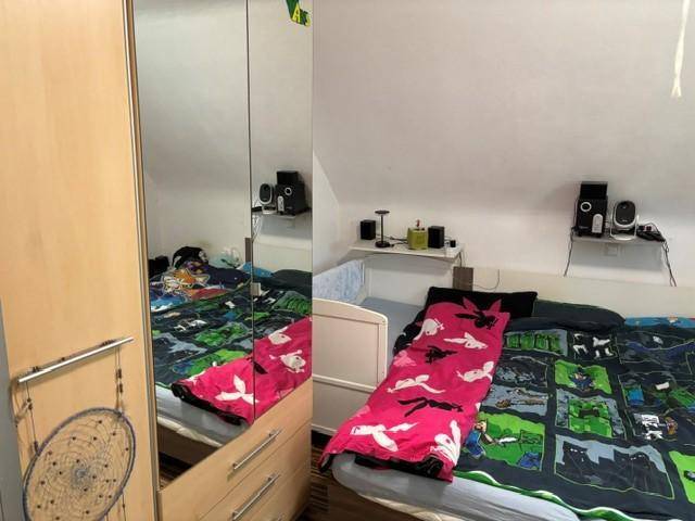 Schlafzimmer mit Bett, Spiegelschrank und Dachschräge, bietet eine gemütliche Atmosphäre.
