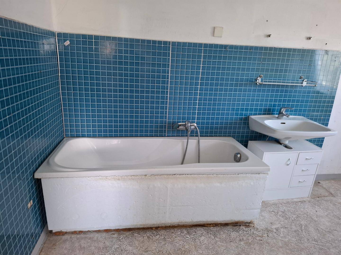Badezimmer mit blauen Fliesen, Badewanne und Waschbecken.
