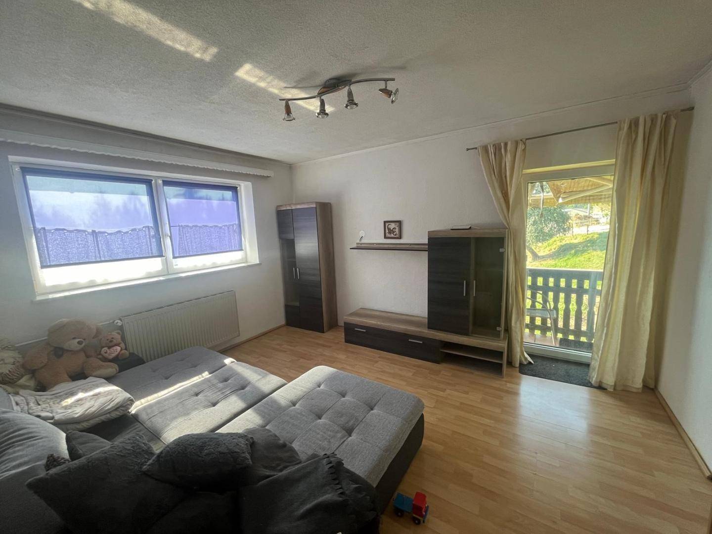 Gemütliches Wohnzimmer mit großem Sofa, Medienmöbeln und direktem Zugang zum Balkon.