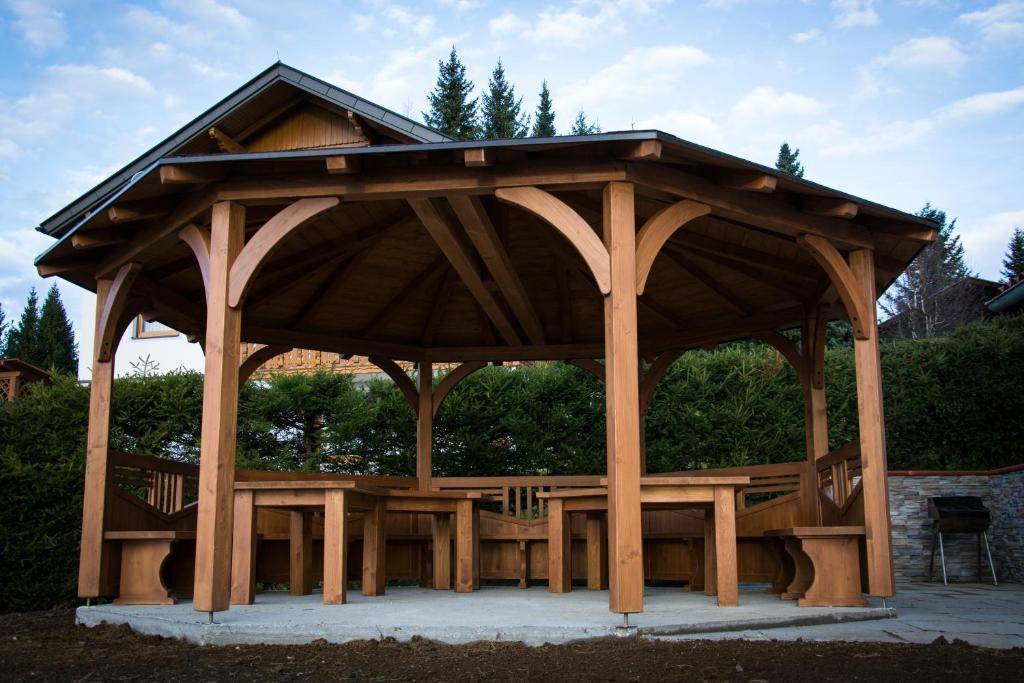 Großer Holzpavillon im Garten mit integrierten Sitzgelegenheiten, ideal für gesellige Stunden.
