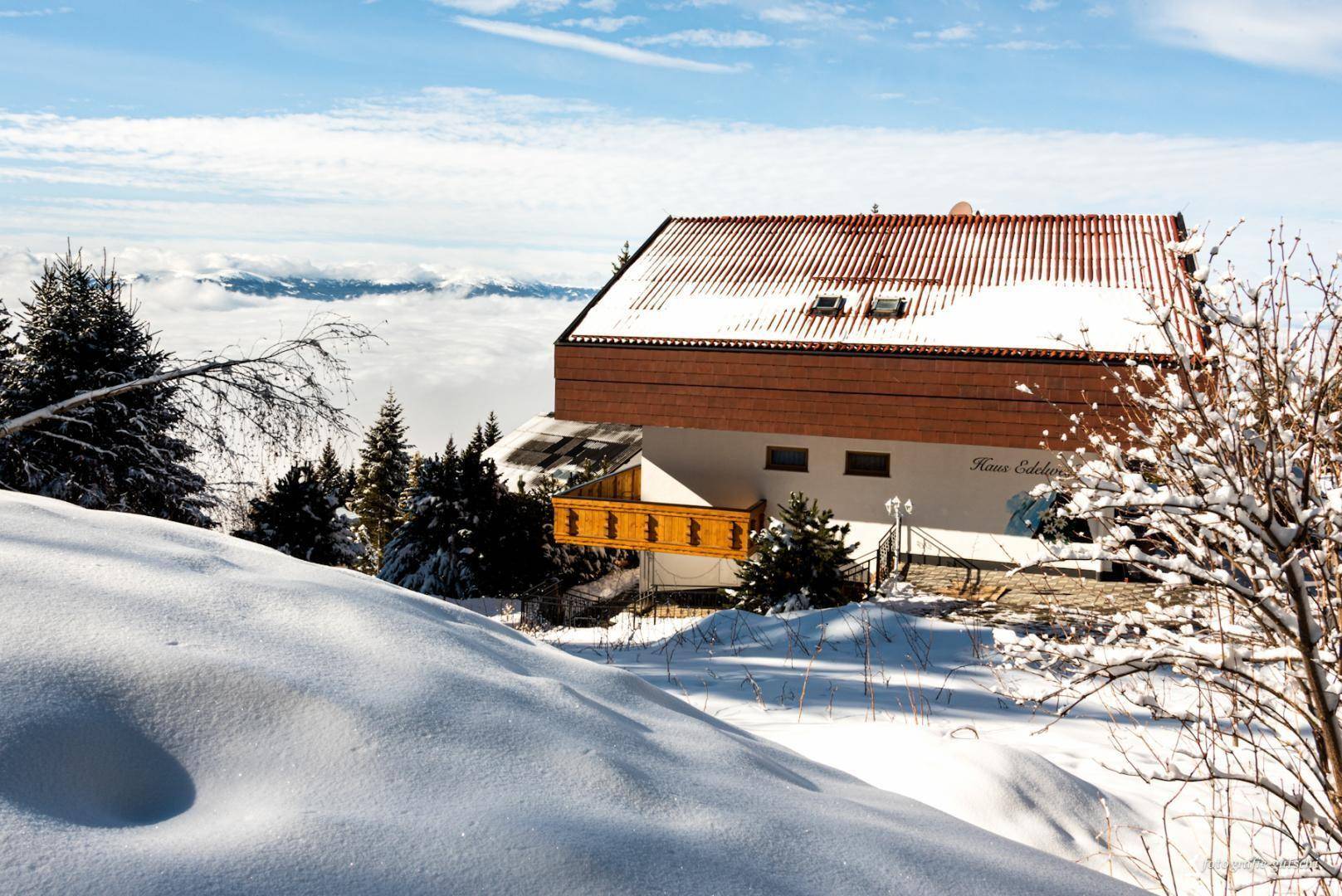 Winterliche Ansicht des Hauses mit verschneiter Landschaft und weitem Bergblick.