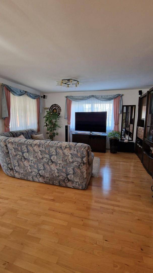 Wohnzimmer mit Holzfußboden, großem Fernseher und einem bequemen Sofa.