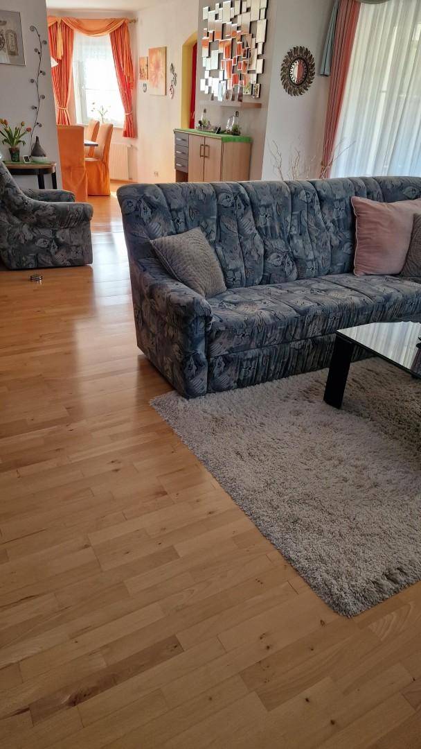 Geräumiges Wohnzimmer mit Holzfußboden, großem Sofa und einem flauschigen Teppich.