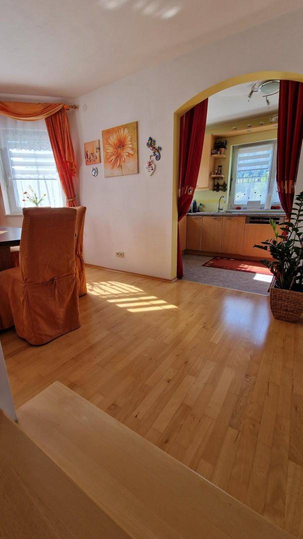 Essbereich mit Holzfußboden und Blick durch einen Bogen in die angrenzende Küche.