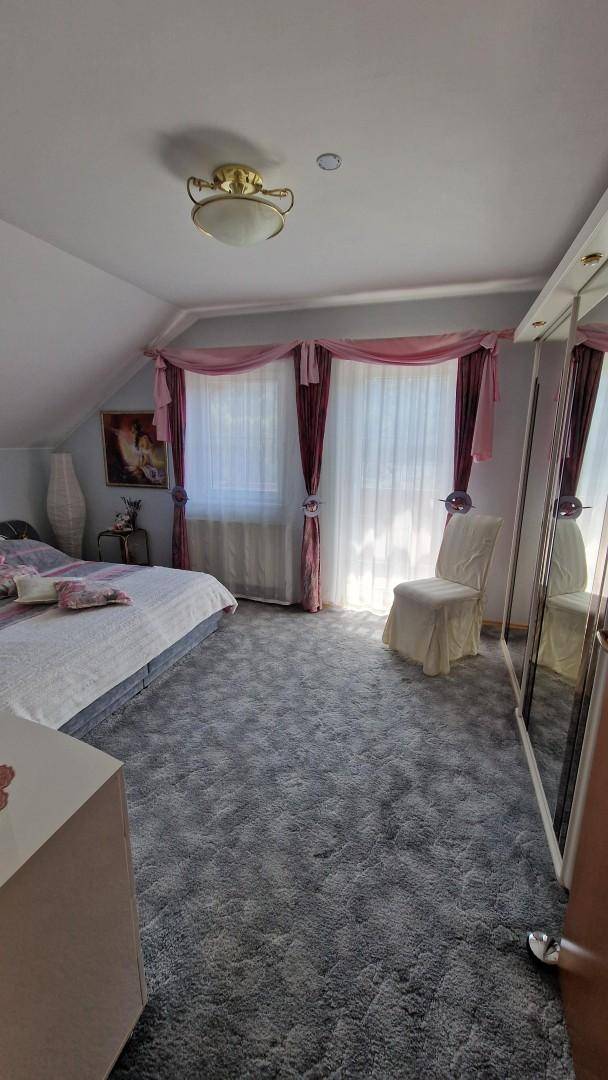 Gemütliches Schlafzimmer im Dachgeschoss mit Teppichboden, Dachschräge und Fensterdekoration.