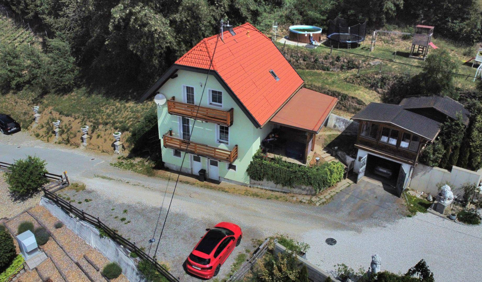 Vogelperspektive des Hauses mit hellgrüner Fassade, Balkonen und Zufahrt in ländlicher Umgebung.
