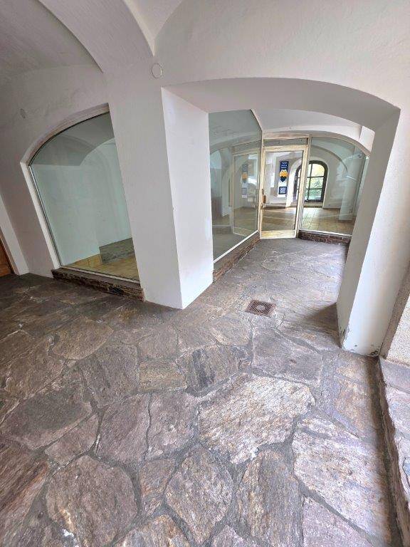 Innenansicht eines Gewerberaums mit unregelmäßigem Steinboden und gewölbten Decken, Blick zum Eingang.