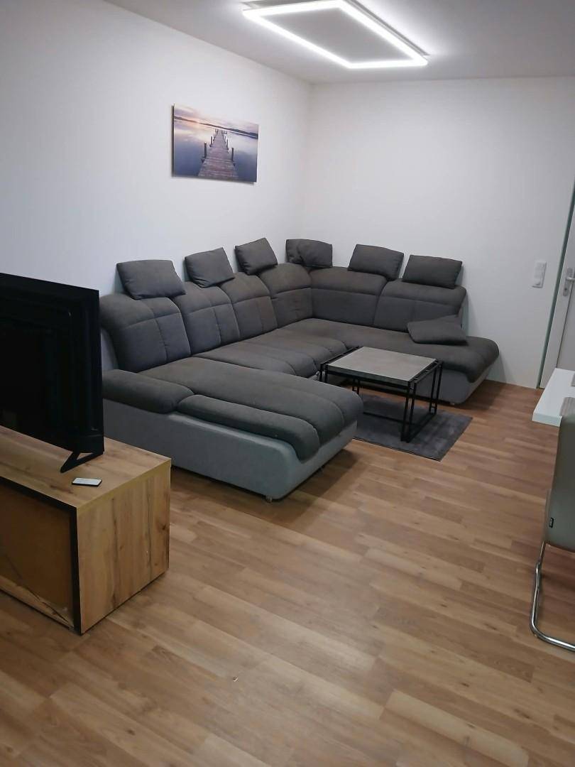 Gemütliches Wohnzimmer mit großem Ecksofa, Couchtisch und Holzboden.